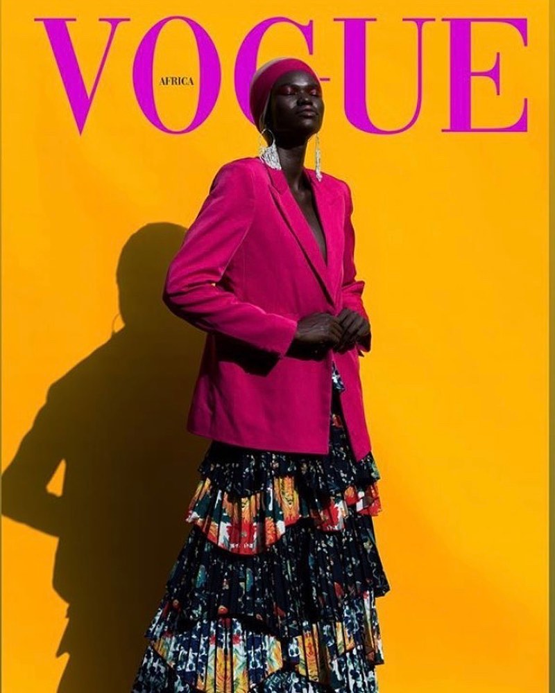Editorial Vogue Africa cover concept: model in magenta tailoring and headwrap against a yellow field with masthead typography