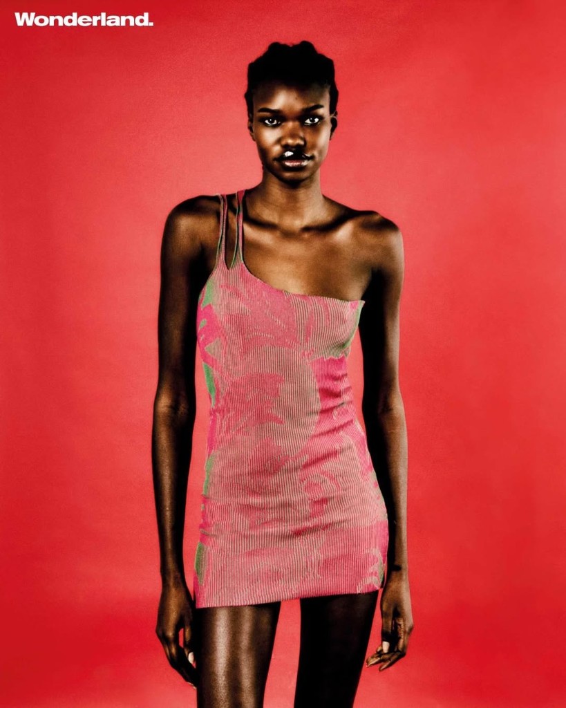 Wonderland editorial: full-length portrait on red seamless backdrop in pink patterned mini dress and orange Chikari boots