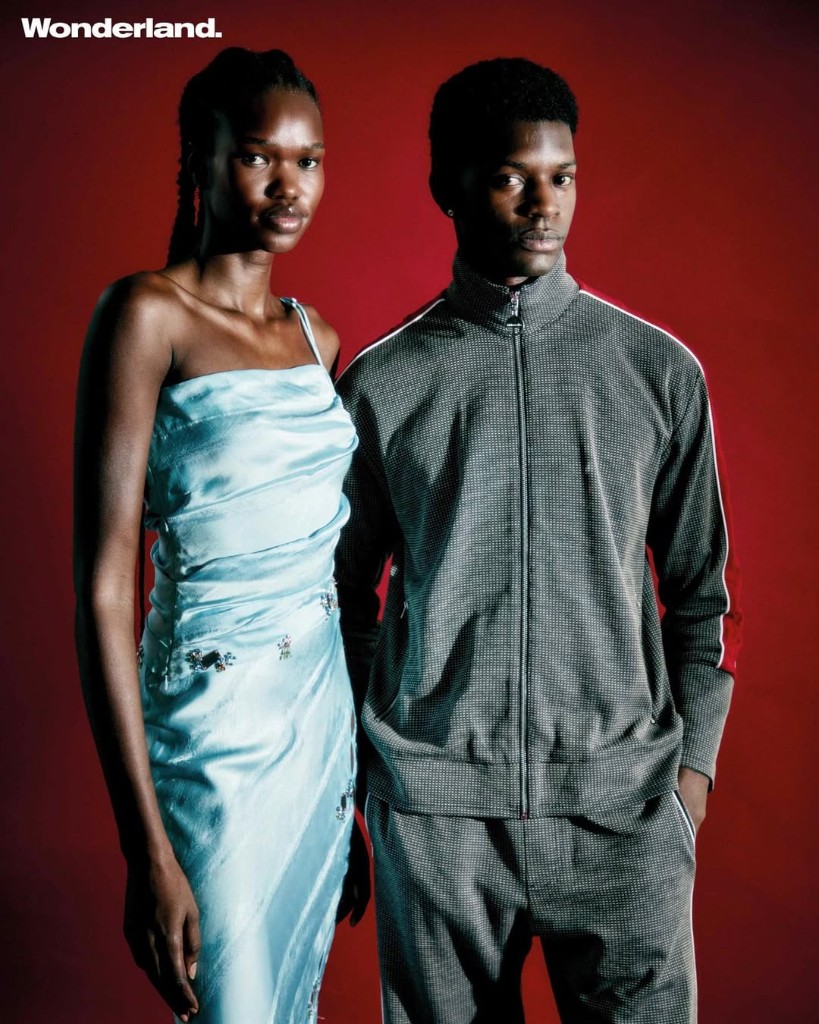 Wonderland editorial: full-length portrait in pale blue one-shoulder midi and patchwork knee boots on red seamless